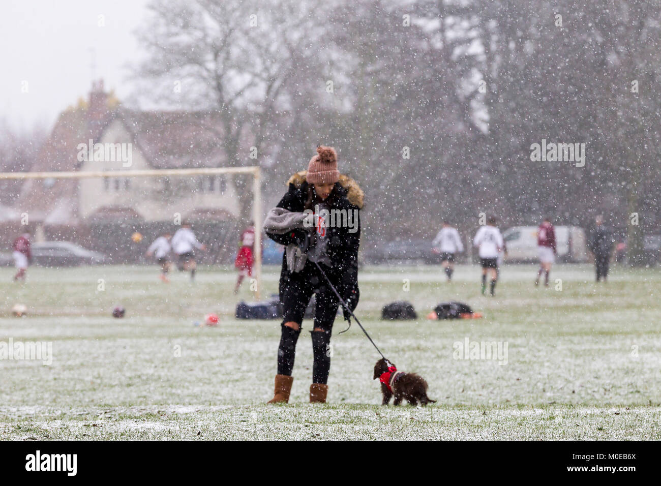 Northampton. U.K.  Weather, Abington park. 21st January 2018. Sleet and Show this morning is not deterring this lady from walking her dog while local footballs play in the background. The forecast is rain this afternoon. Credit: Keith J Smith./Alamy Live News Stock Photo