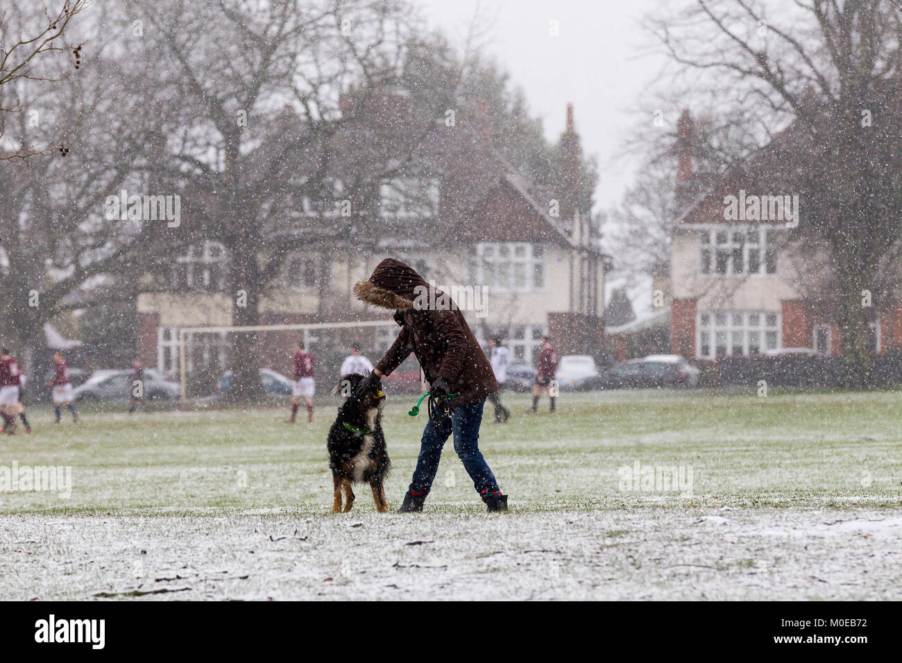 Northampton. U.K.  Weather, Abington park. 21st January 2018. Sleet and Show this morning is not deterring this lady from walking her dog while local footballs play in the background. The forecast is rain this afternoon. Credit: Keith J Smith./Alamy Live News Stock Photo