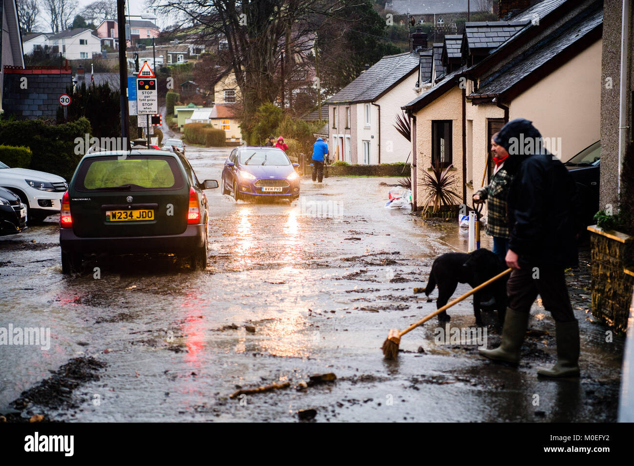 Llandre, Ceredigion Wales, Sunday 21 January 2018  UK Weather: Flood water cascade like a river down the main street in LLANDRE near Aberystwyth in Mid Wales, after hours of torrential rain caused the small steam that runs through he village to dramatically burst its banks . Local residents  made improvised sandbags and barriers to try to divert the water away from their houses. The stream overflowed high above the village just outside the parish church, sending debris down and washing away parts of the road surface    photo © Keith Morris / Alamy Live News Stock Photo