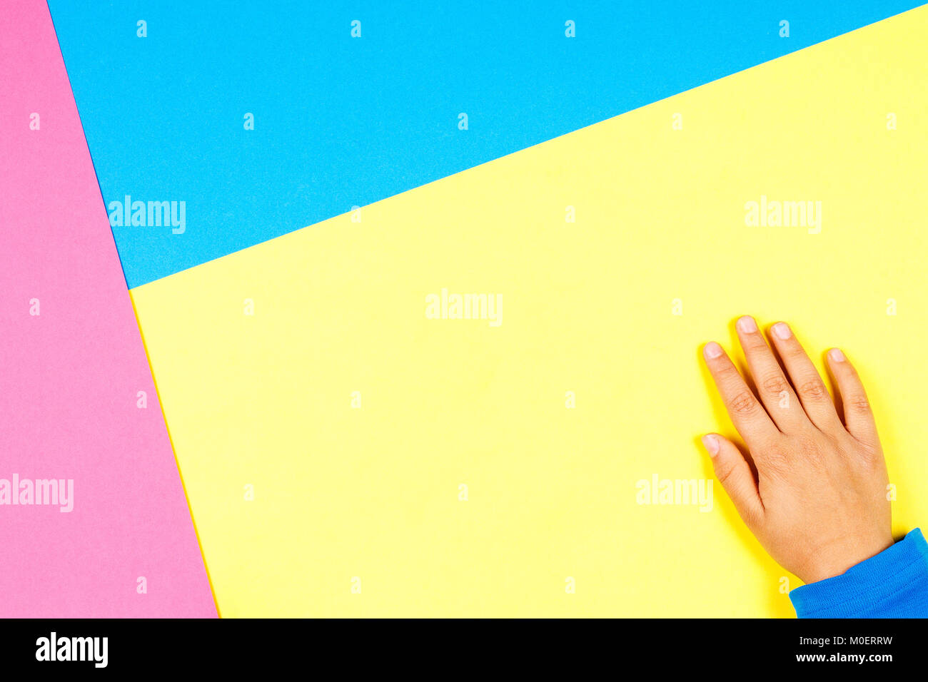 Kid hand on yellow, blue and pink background. Stock Photo