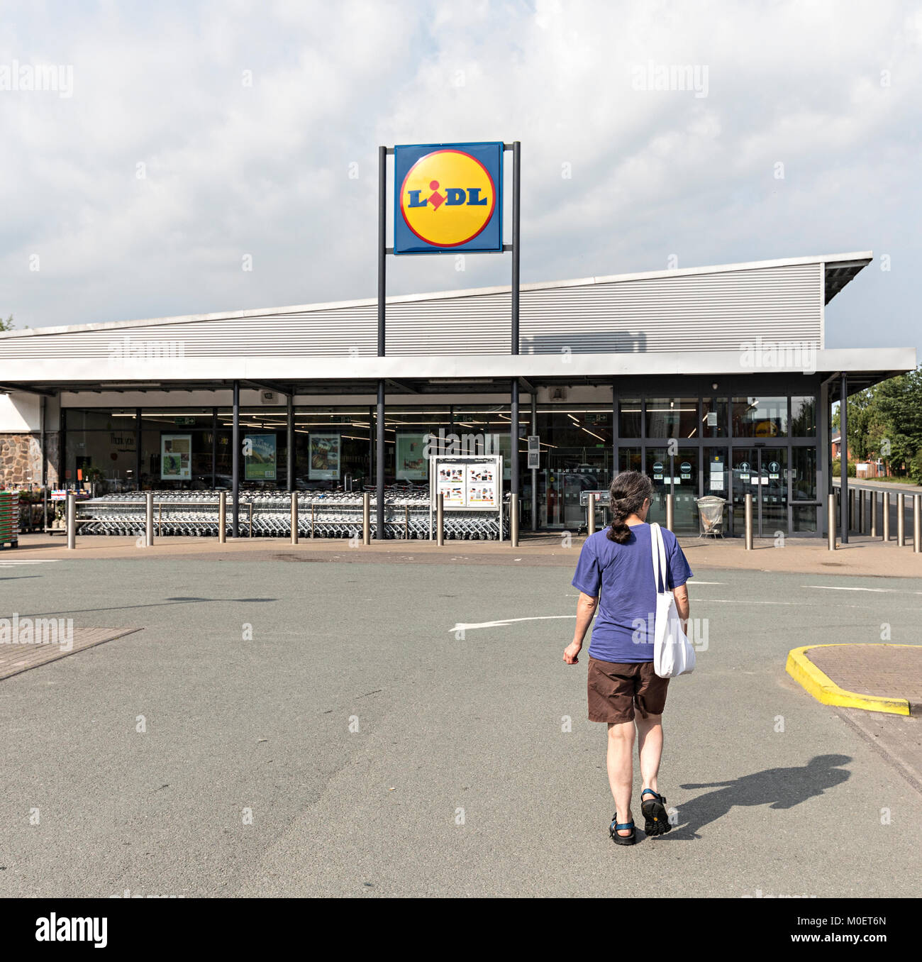 Woman walking towards a Lidl supermarket, Newtown, Powys, Wales, UK Stock Photo