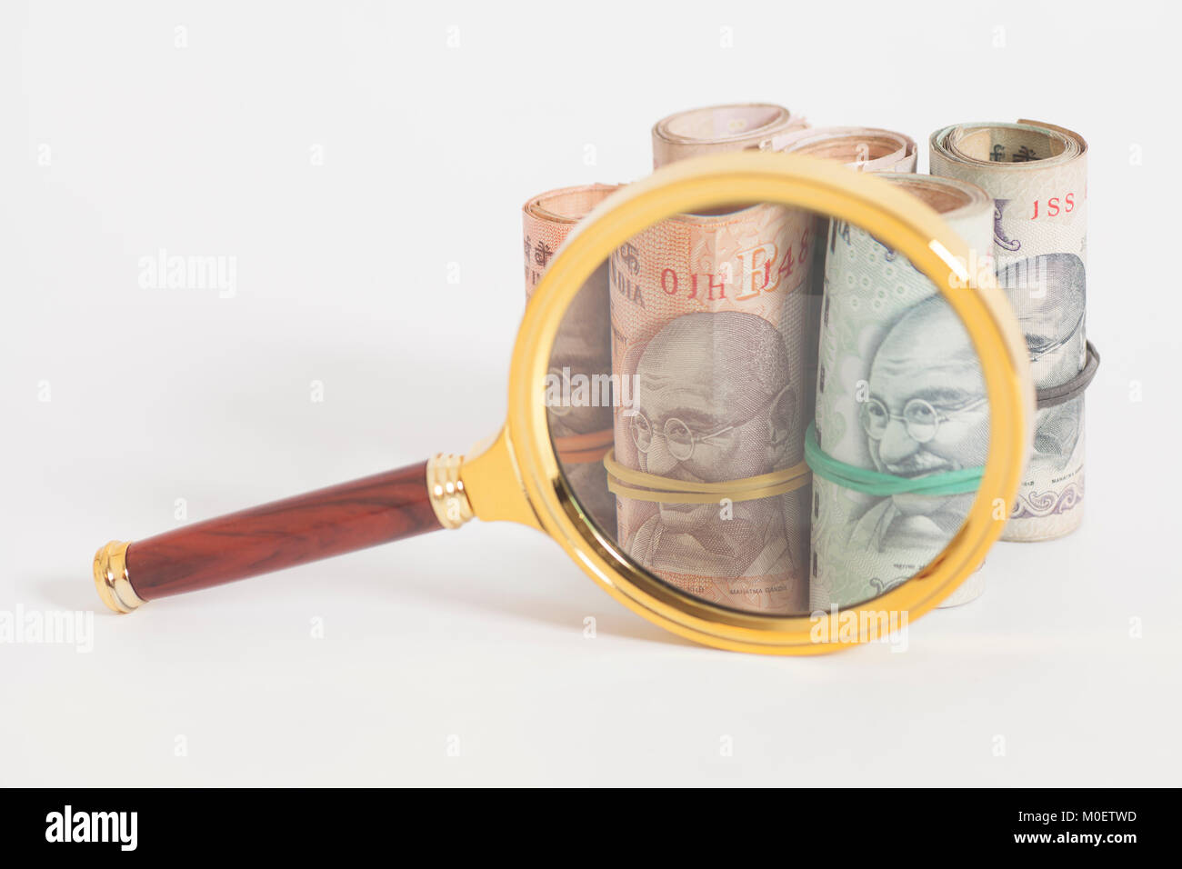 Rolls of Indian Currency Rupee Notes with magnifying glass isolated on ...