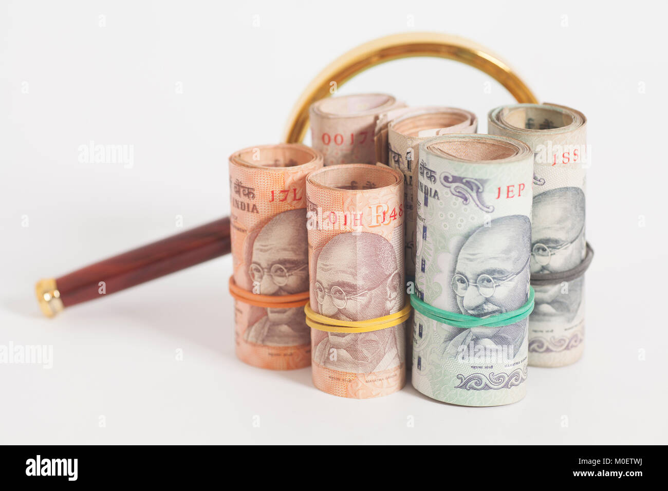Rolls of Indian Currency Rupee Notes with magnifying glass isolated on ...
