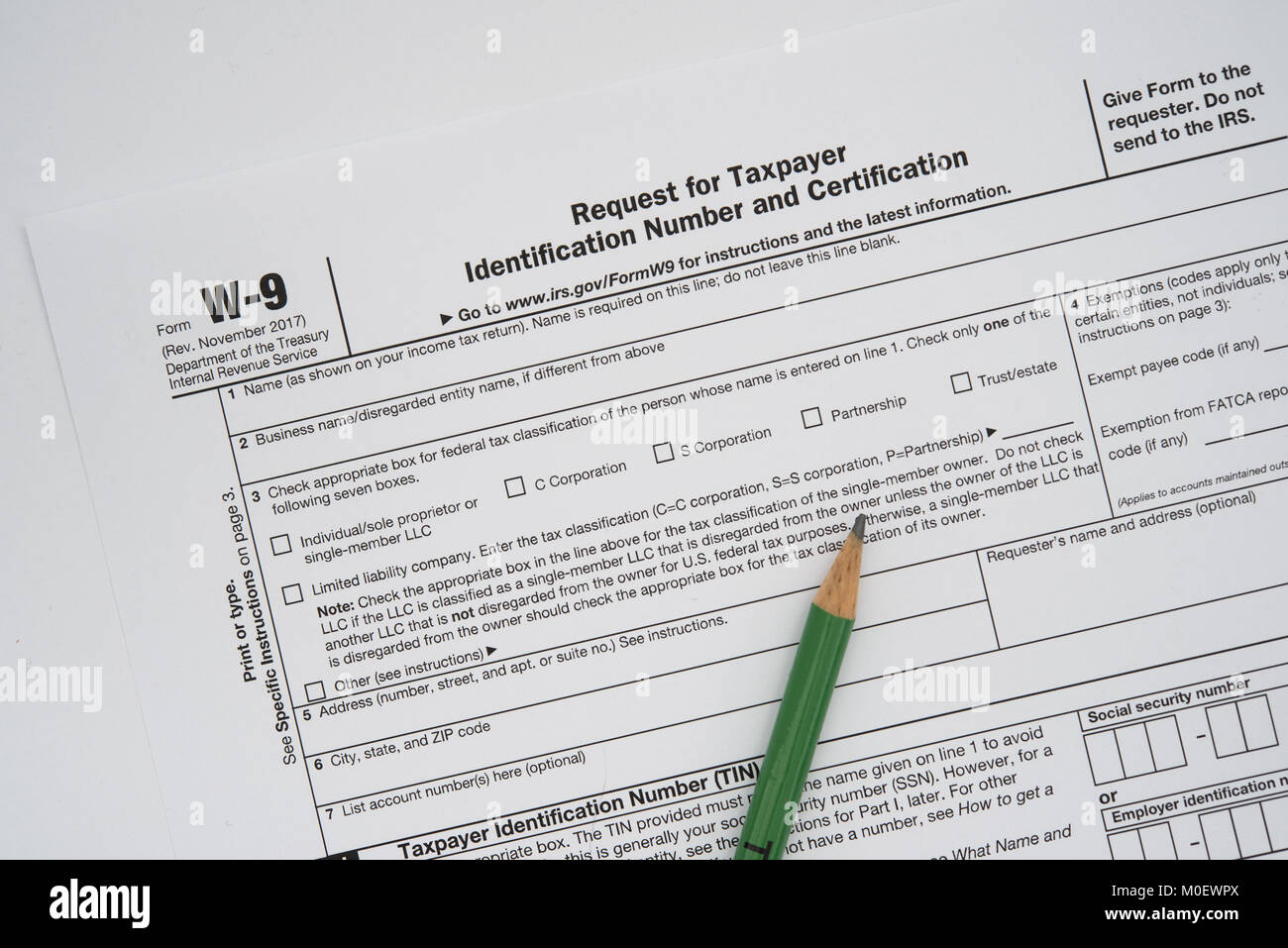 A US form W-9, request for taxpayer identification number and certification, with a green pencil. Stock Photo