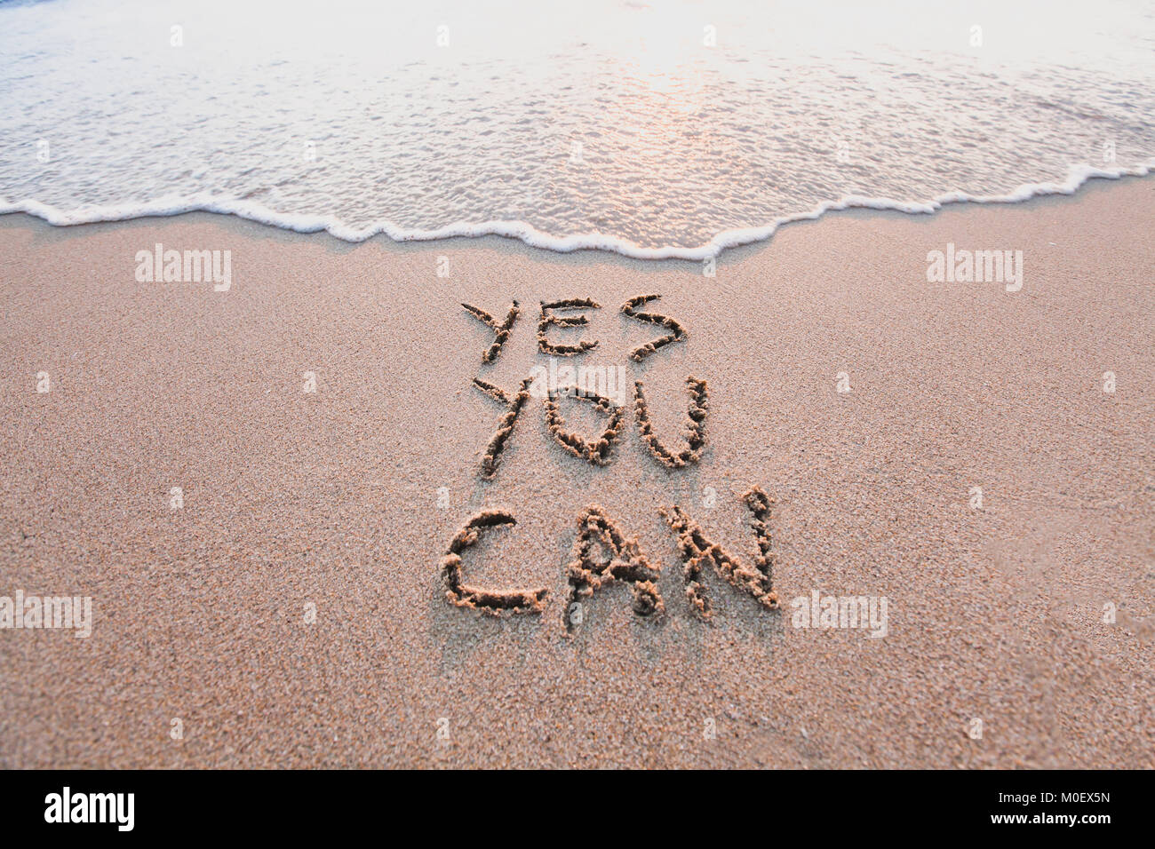 yes you can, motivational inspirational message concept written on the sand of beach Stock Photo