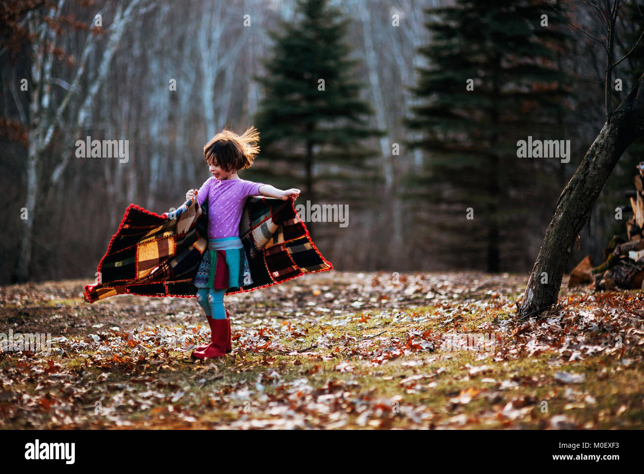 Girl wrapped in a blanket spinning around in forest Stock Photo