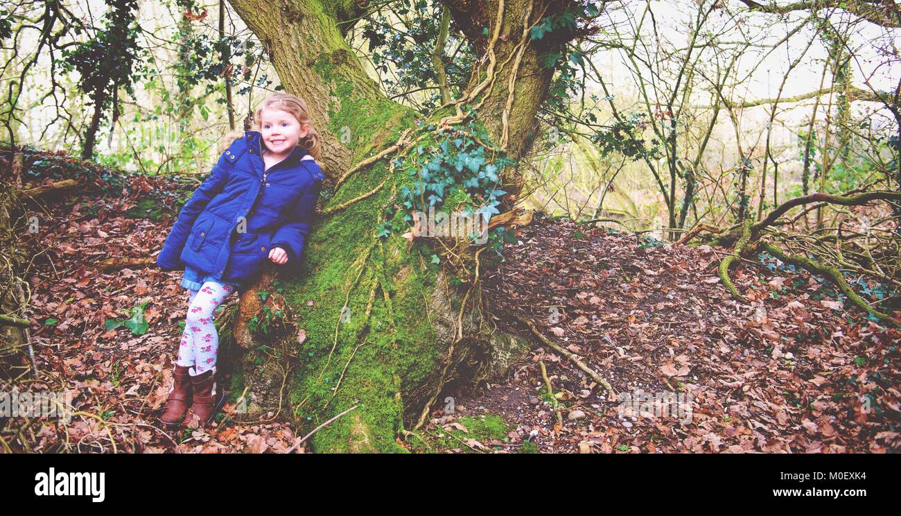 Girl standing in forest leaning against a tree, Kingsbury, Warwickshire, England, United Kingdom Stock Photo