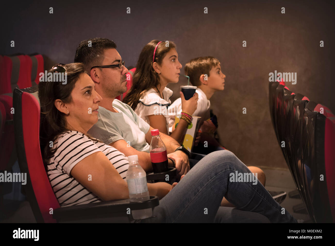 Family sitting in a cinema watching a movie Stock Photo