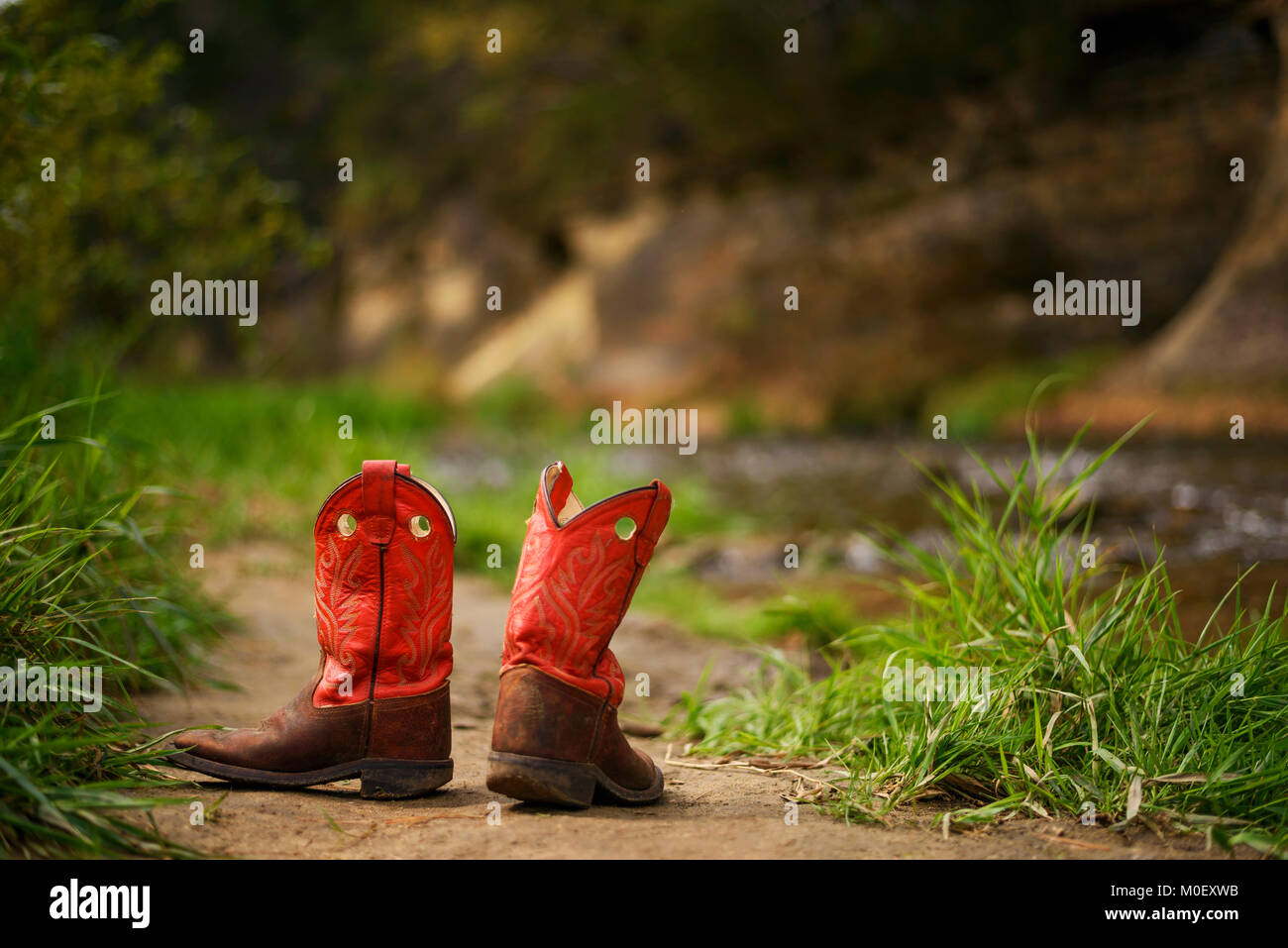 Pair of children's cowboy boots by a river Stock Photo
