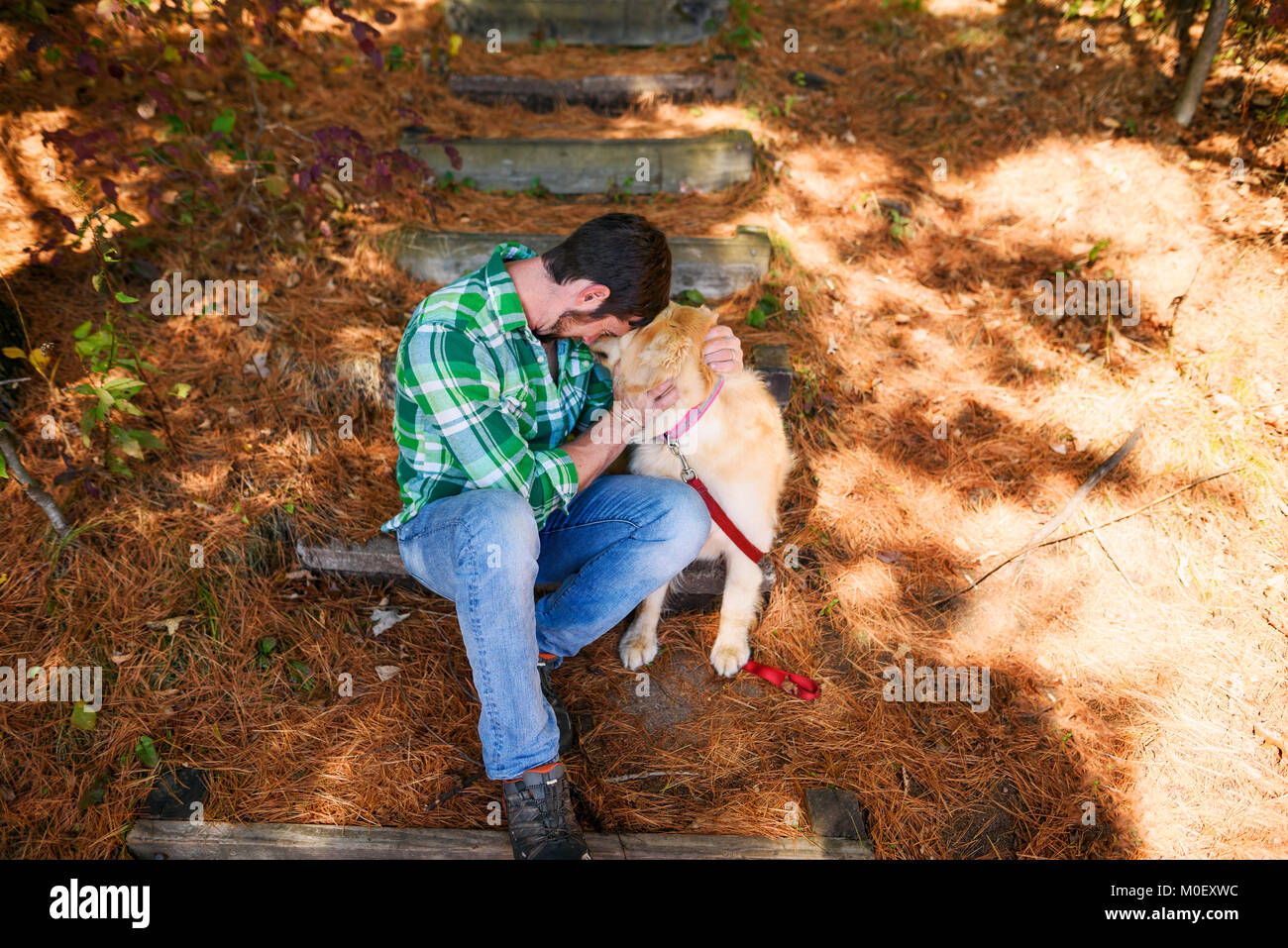 Man sitting outdoors hugging a golden retriever dog Stock Photo