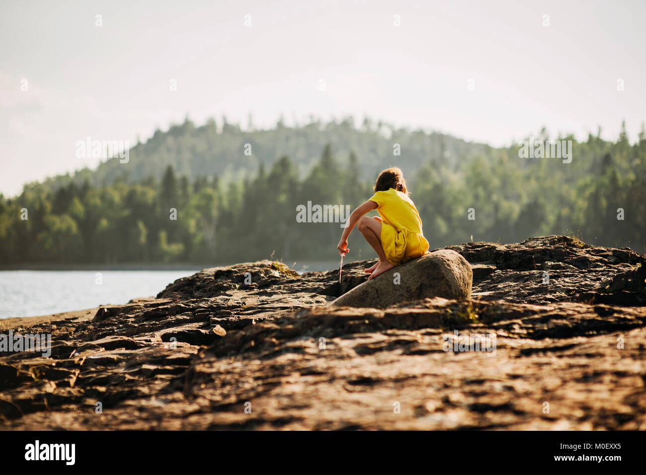 Young girl playing on rocks by a lake Stock Photo