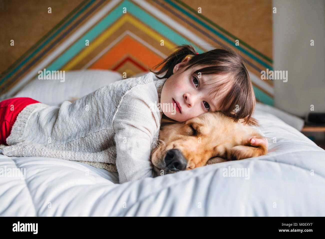 Girl lying on a bed with her golden retriever dog Stock Photo - Alamy