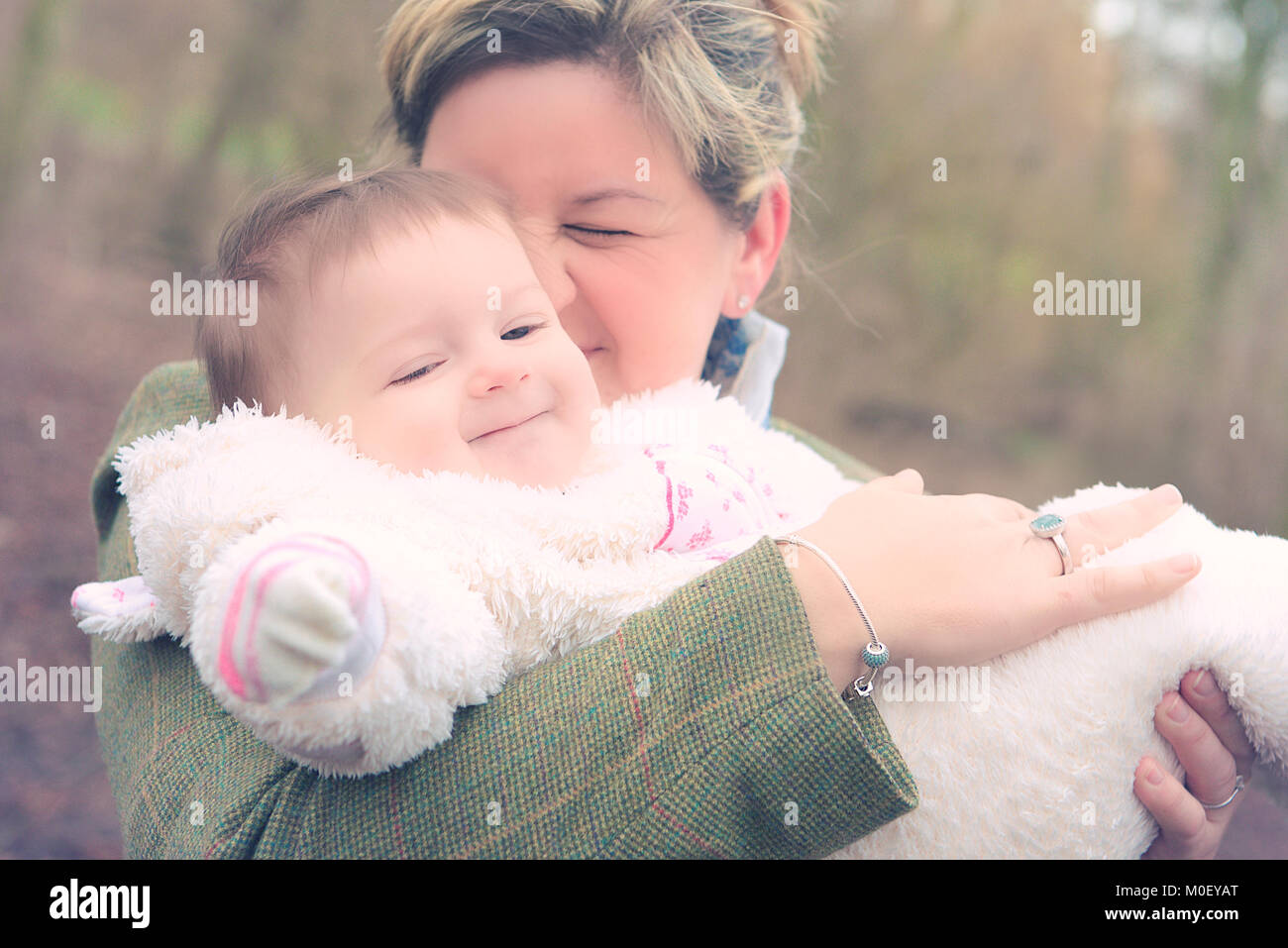 Smiling woman standing in park cuddling her daughter Stock Photo