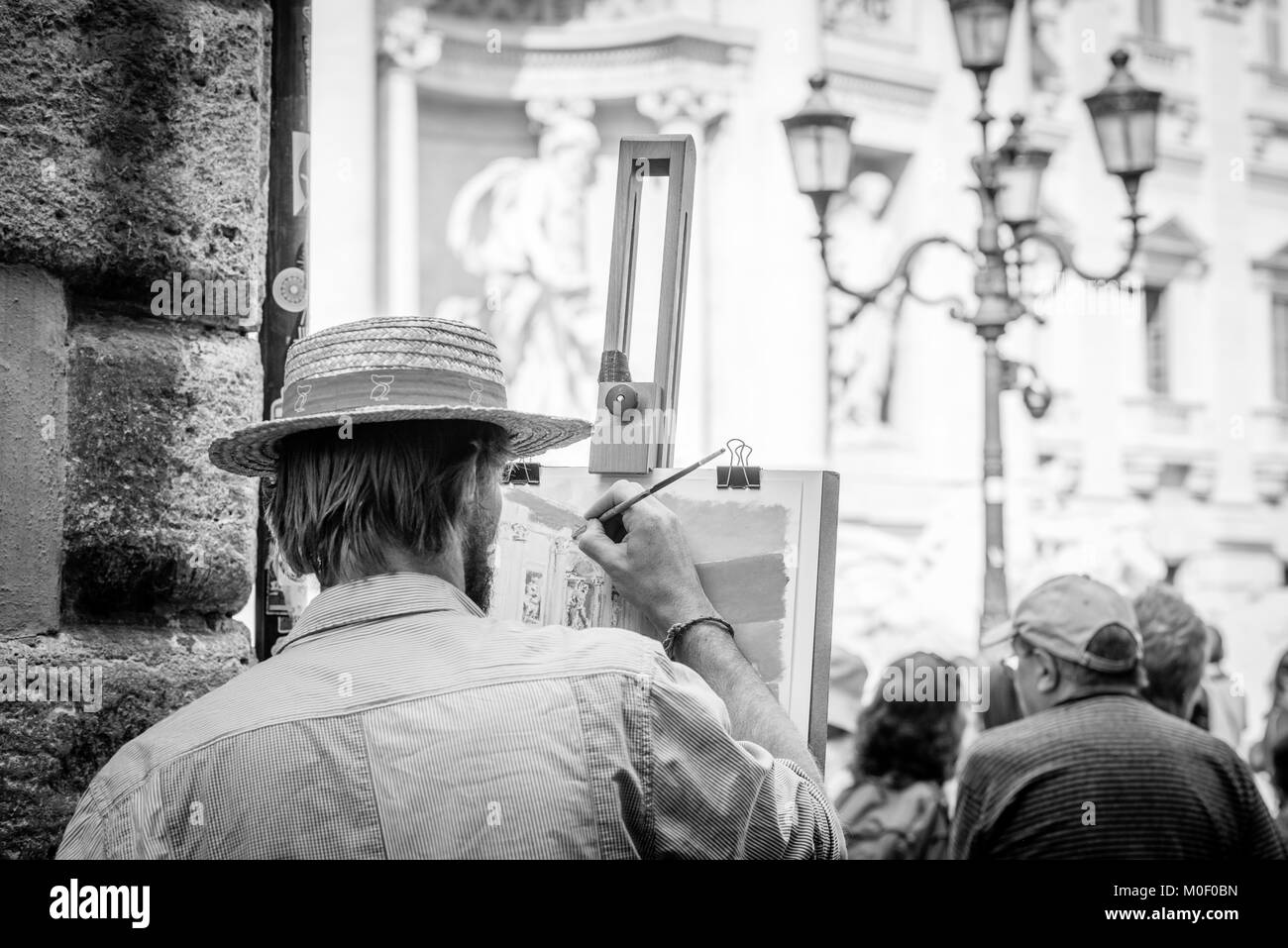 An artist lost in concentration as he paints the Trevi Fountains in Rome Stock Photo