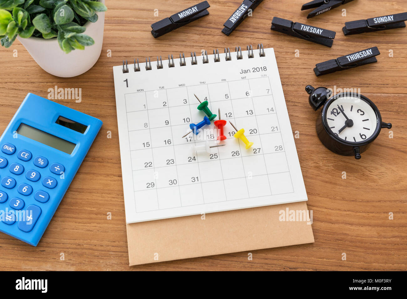 Calendar with pins on desk with clock and calculator Stock Photo