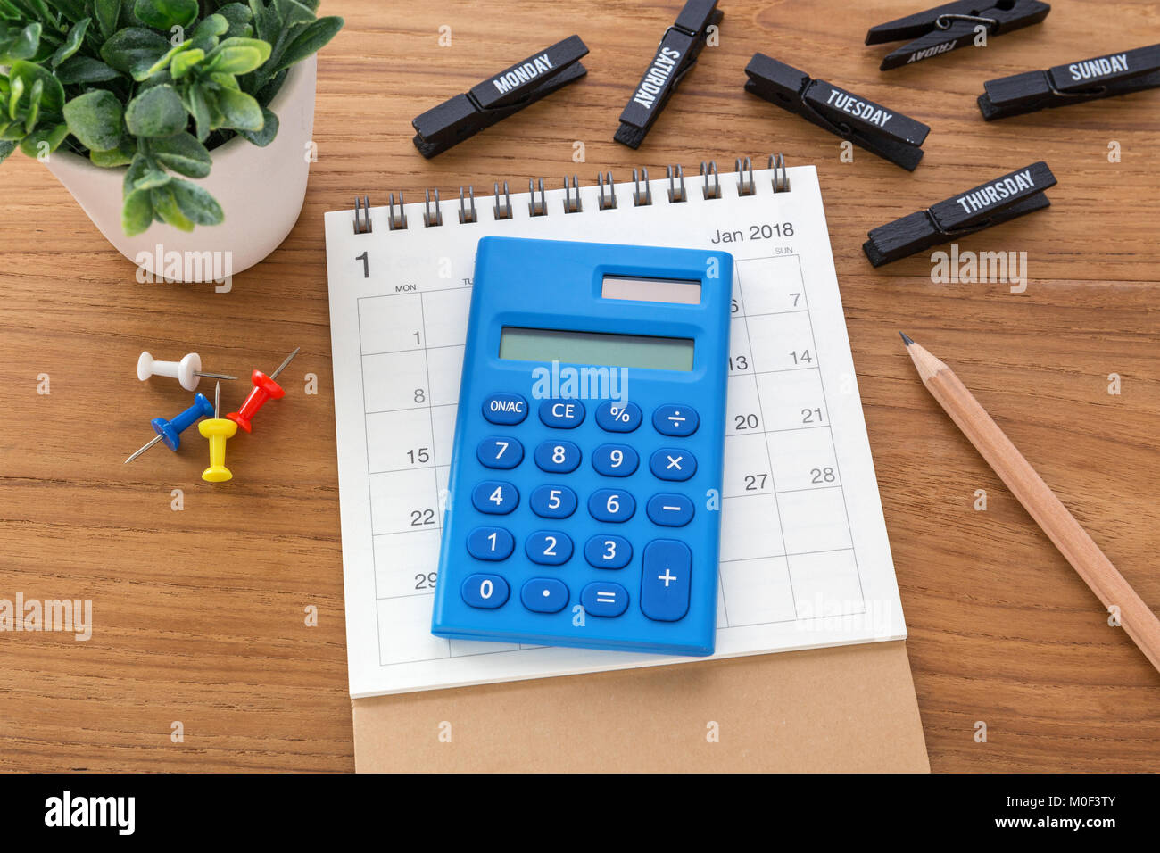 Calculator on calendar with pen on wooden table Stock Photo
