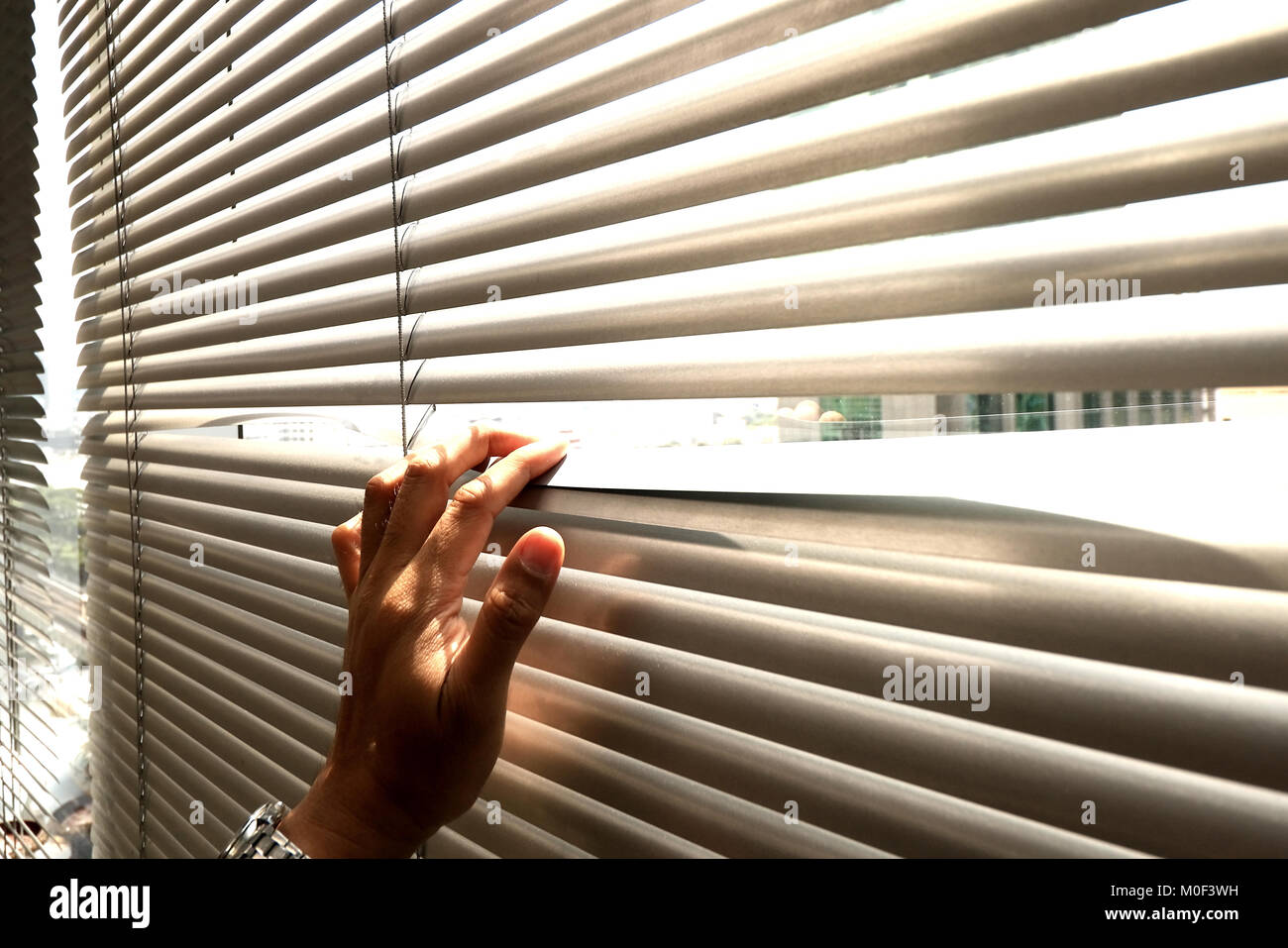Hand taking a peek through the window blinds Stock Photo Alamy