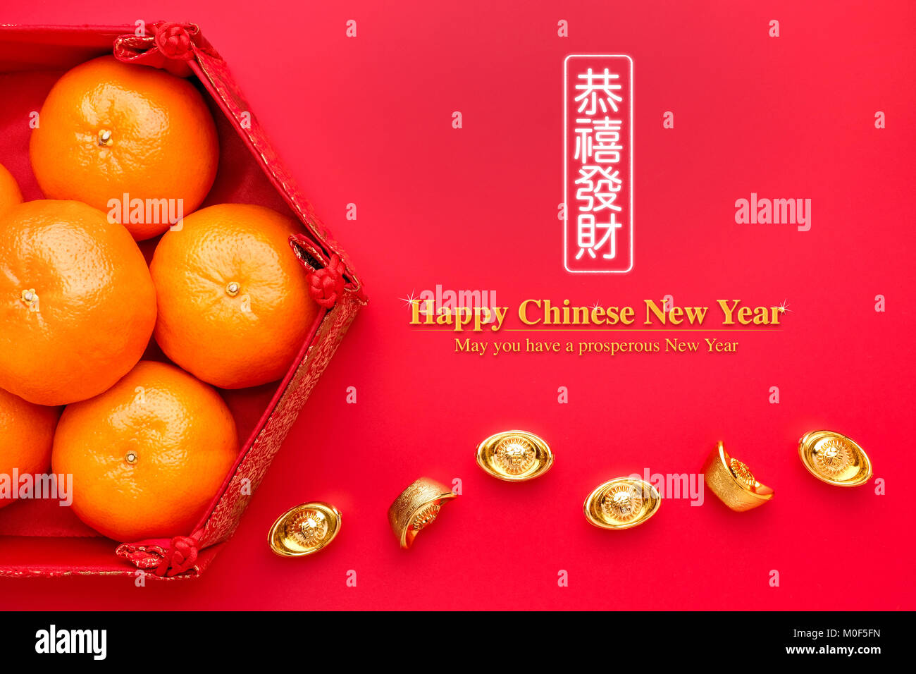 Group of orange tangerine in Chinese pattern tray with gold ingots on