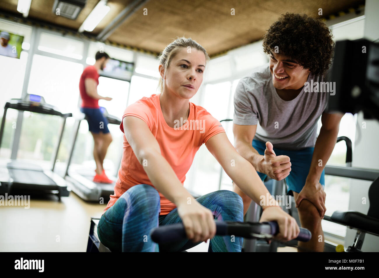 Young beautiful woman doing exercises with personal trainer Stock Photo