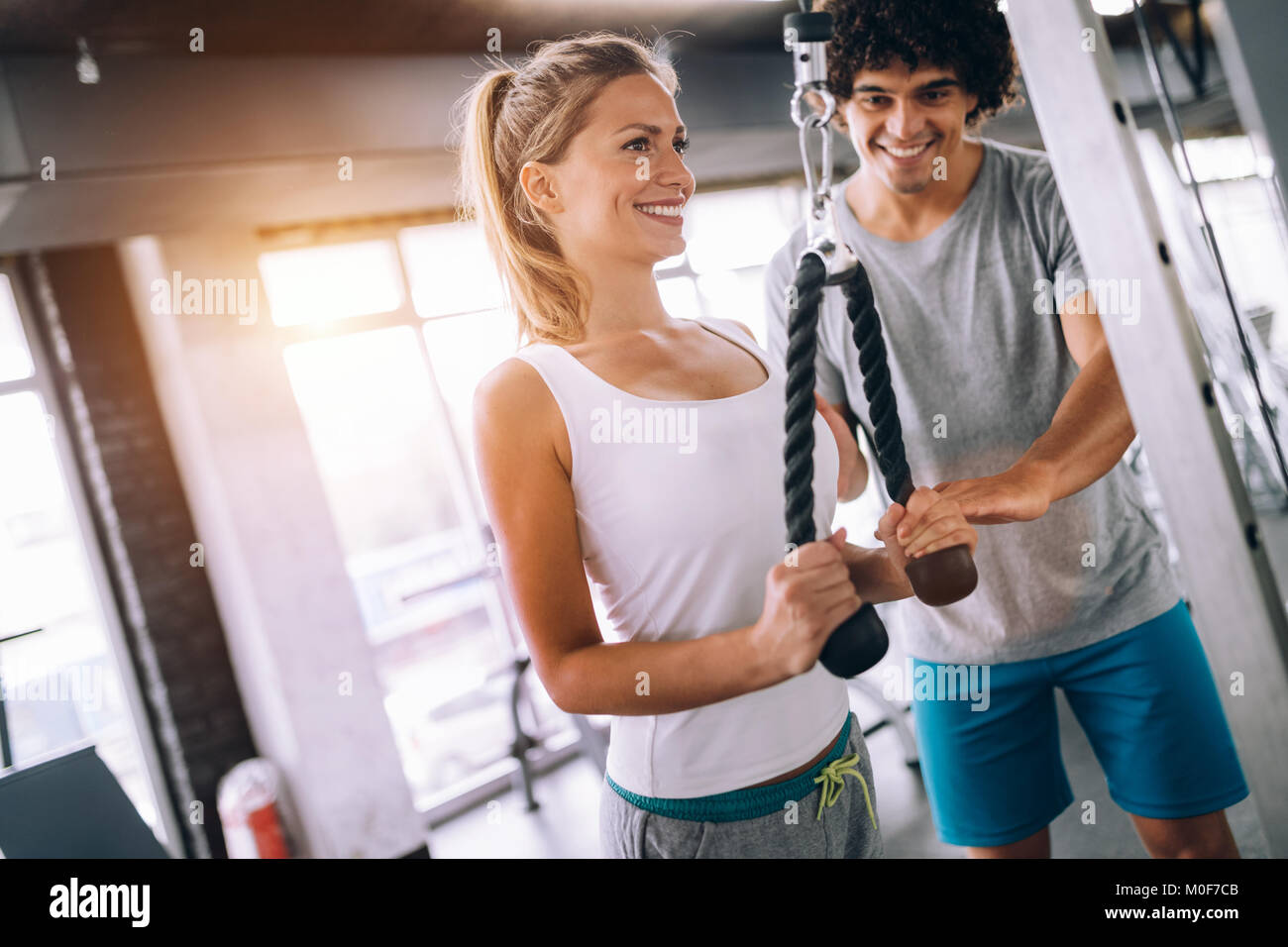 Young beautiful woman doing exercises with personal trainer Stock Photo