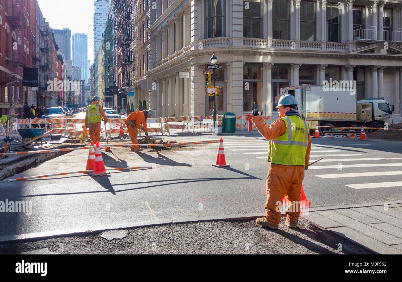 Construction workers in safety clothing and helmets digging up the street in SoHo, New York City Stock Photo
