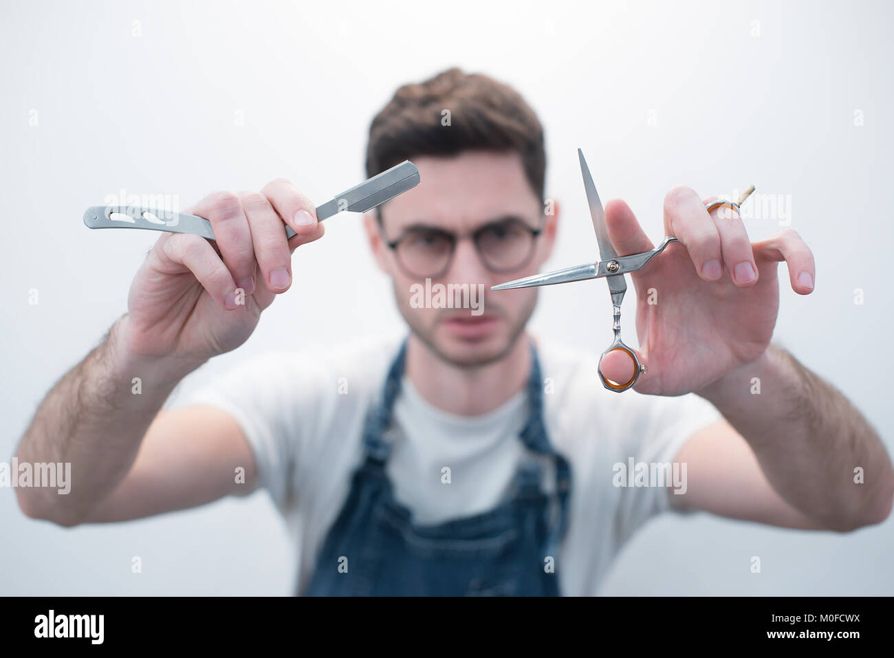 Barber keeps scissors and a razor against the background of a white