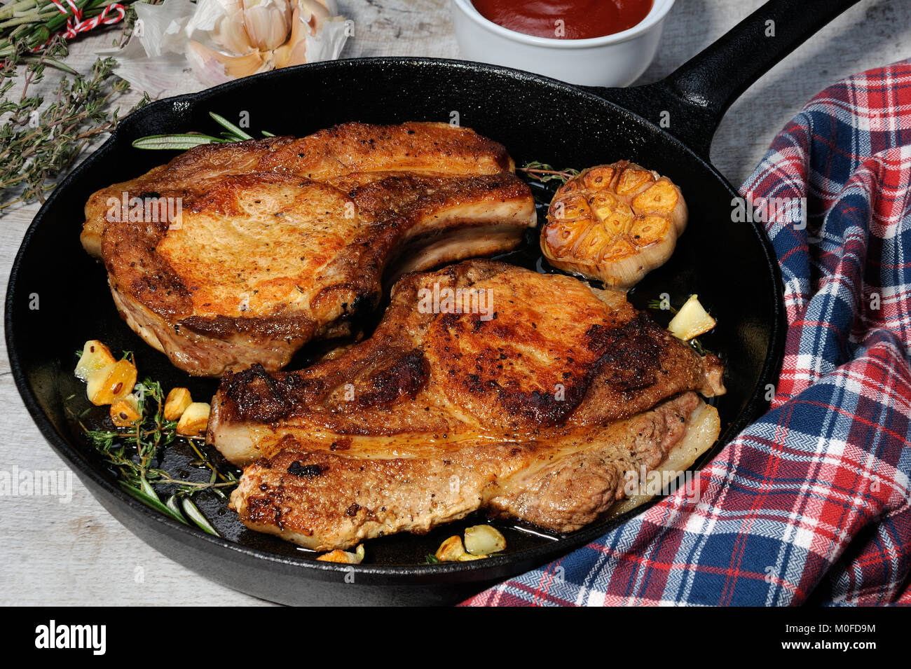 Roasted pork loin steak in a frying pan with tomato sauce Stock Photo