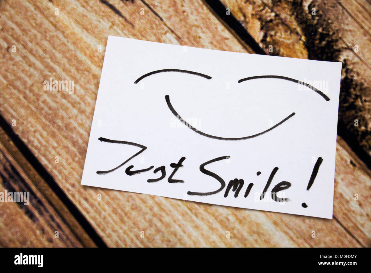 Top view of Just Smile sticky note on the wooden desk with smile icone ...