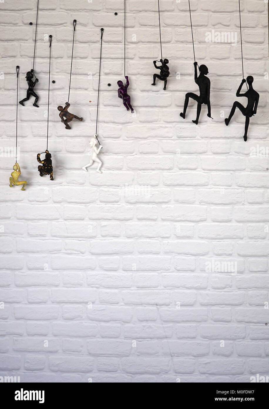 Human figurines climbing up a brick wall (concept) Stock Photo