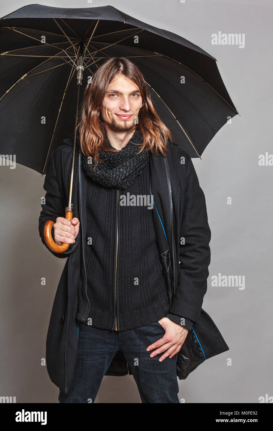 Portrait of handsome fashionable man wearing black coat and scarf ...