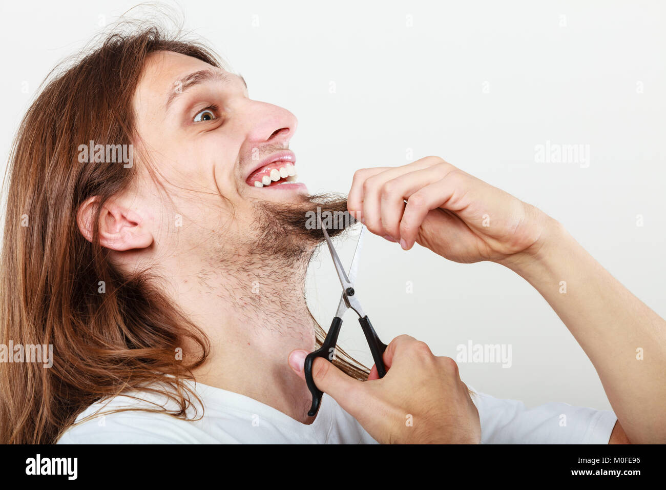 Cut and shave concept. Young man with long beard holding scissors. Boy