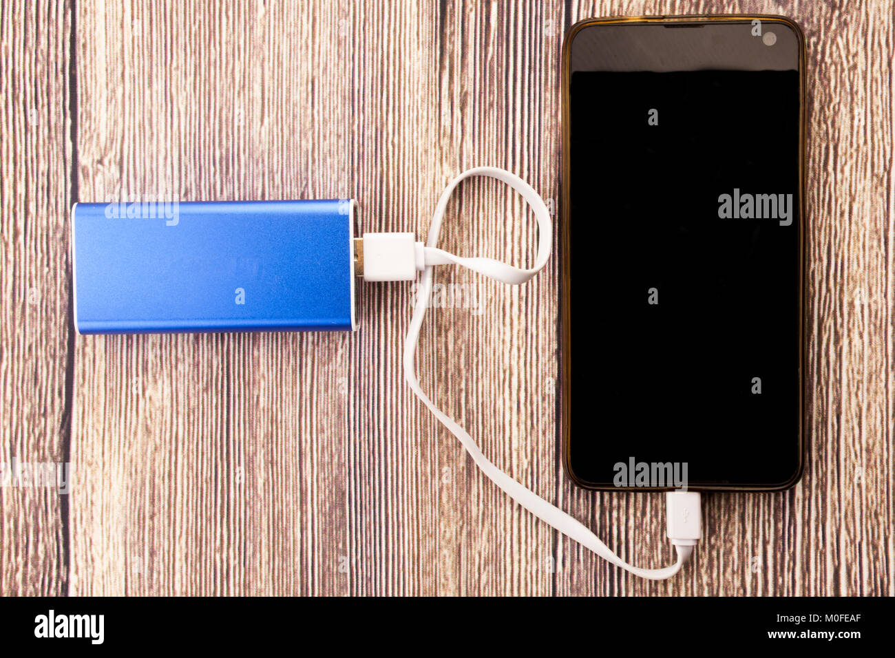 Phone charging with energy bank powerbank. Depth of field on Power bank and cellphone Stock