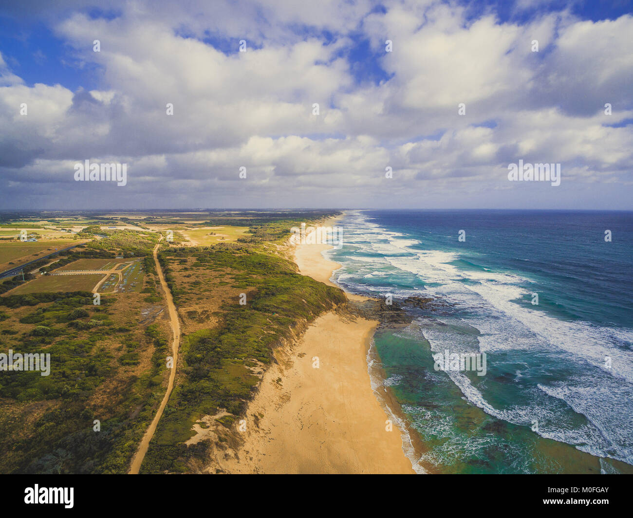 Ocean coastline with rural road and beautiful clouds - aerial landscape of Australia Stock Photo