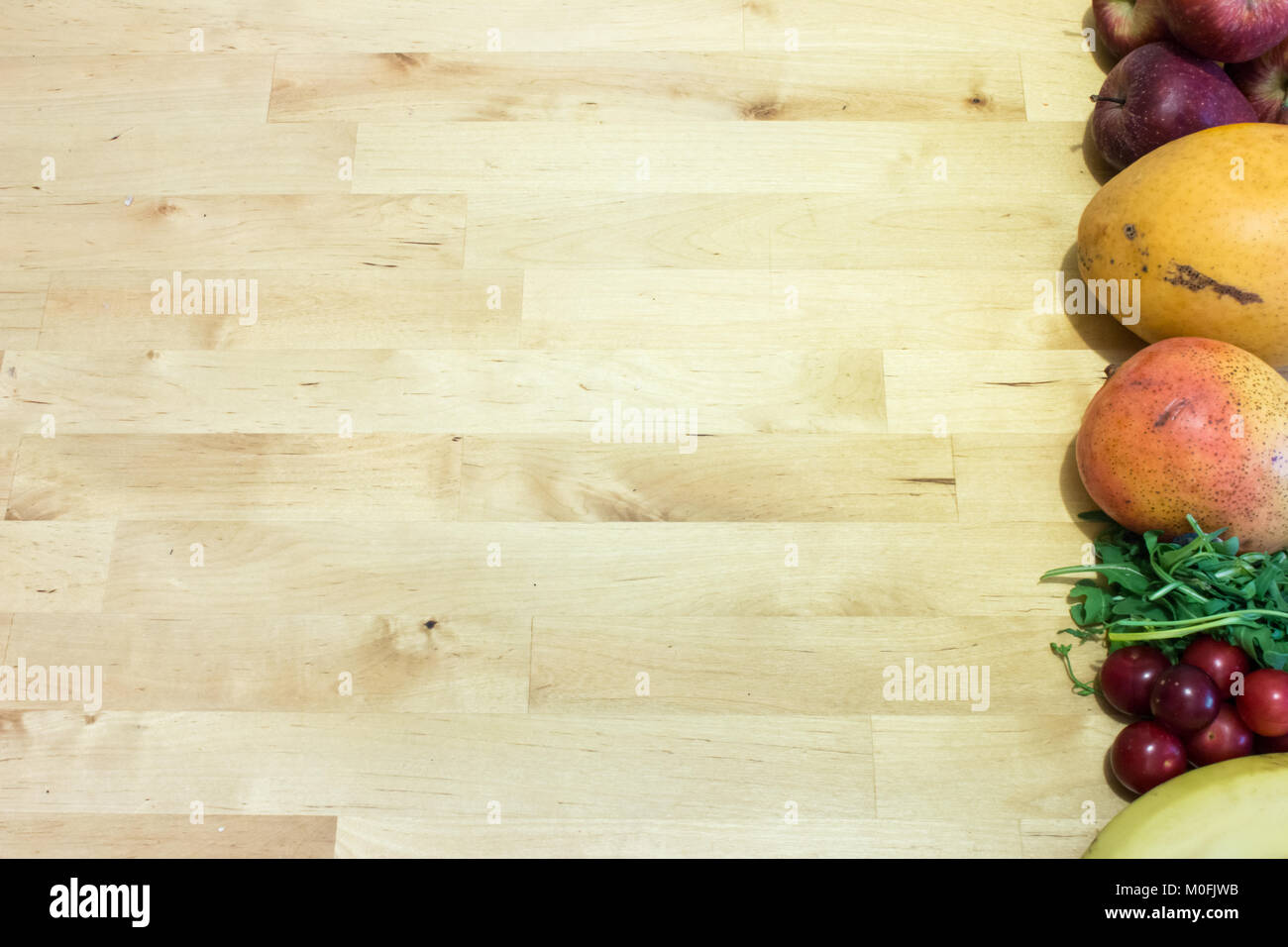 Assortment of ripe fruits (apples, mangoes, plums and banana) on wooden