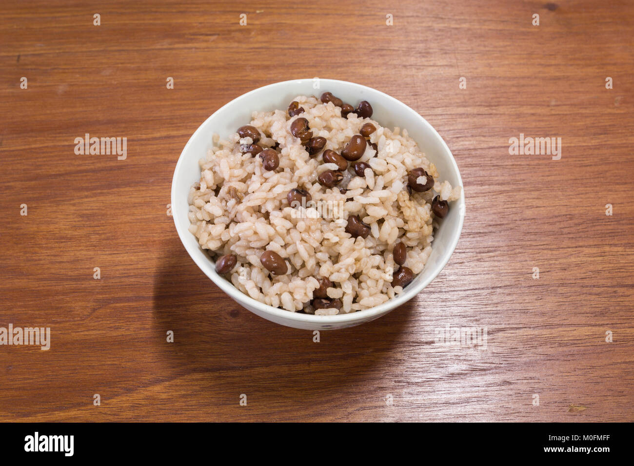 Cooked red beans and Japanese rice in white bowl on wooden table Stock Photo