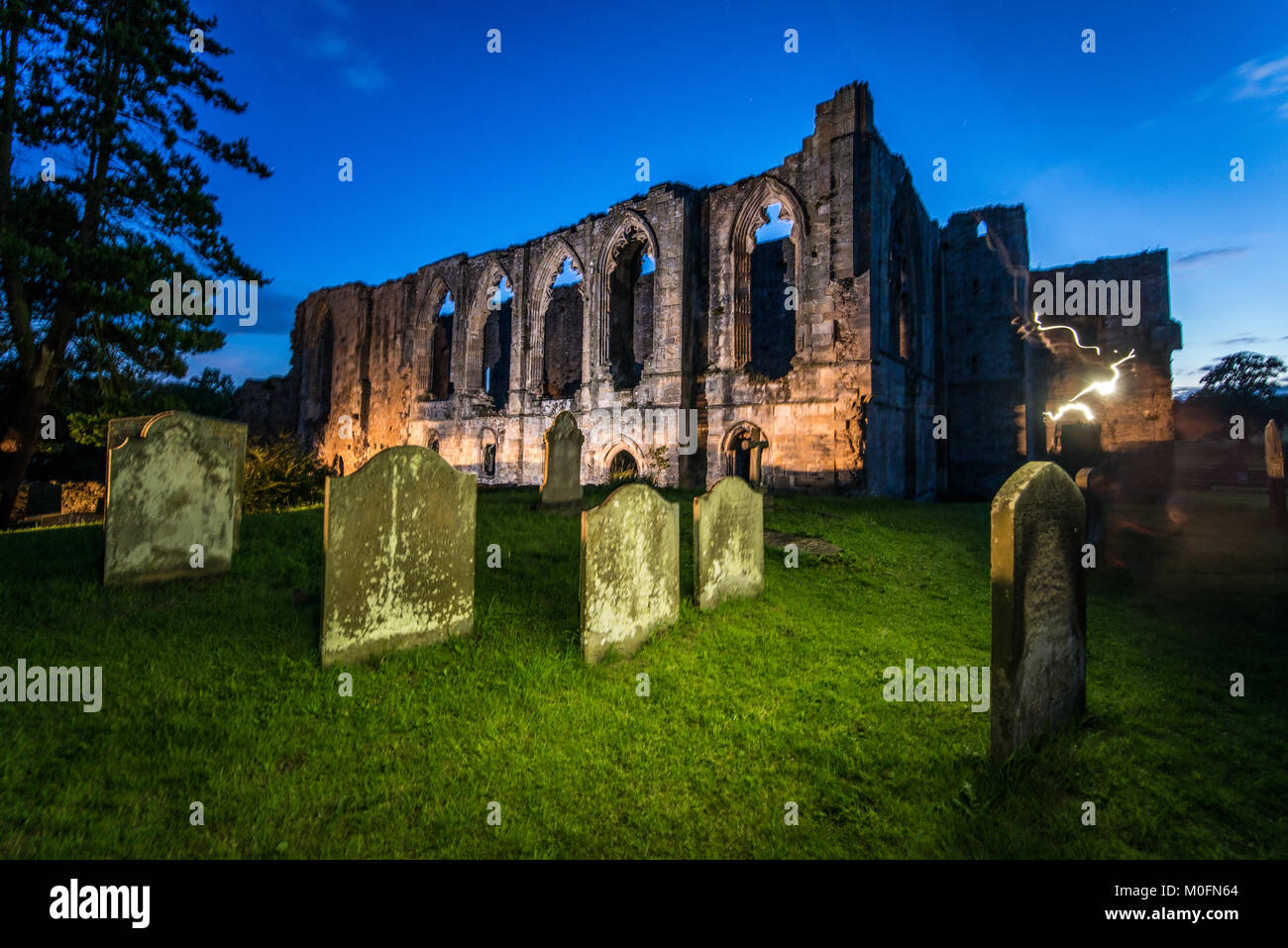 Artificial light used to illuminate graveyard in front of Easby Abbey, Yorkshire, UK Stock Photo
