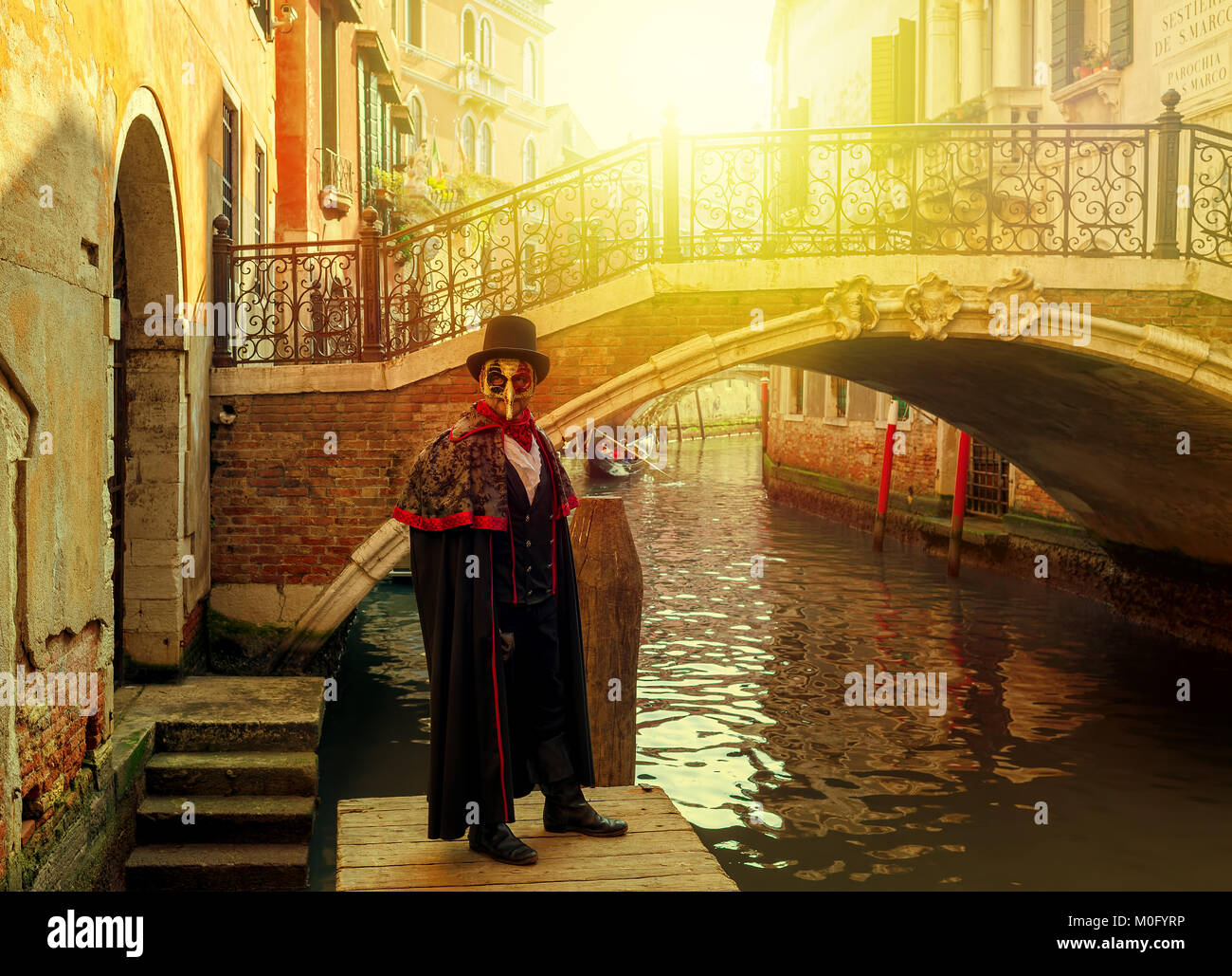 Unidentified man in black costume, hat and mask posing in front of