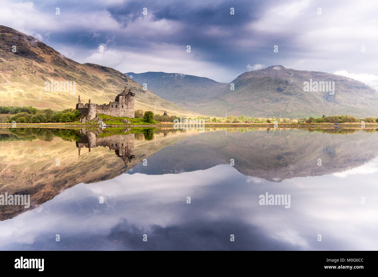 The ruins of Kilchurn Castle, home of the Clan Campbells of Glenorchy, and the mountains of Argyll are reflected in the calm waters of Loch Awe in the Stock Photo