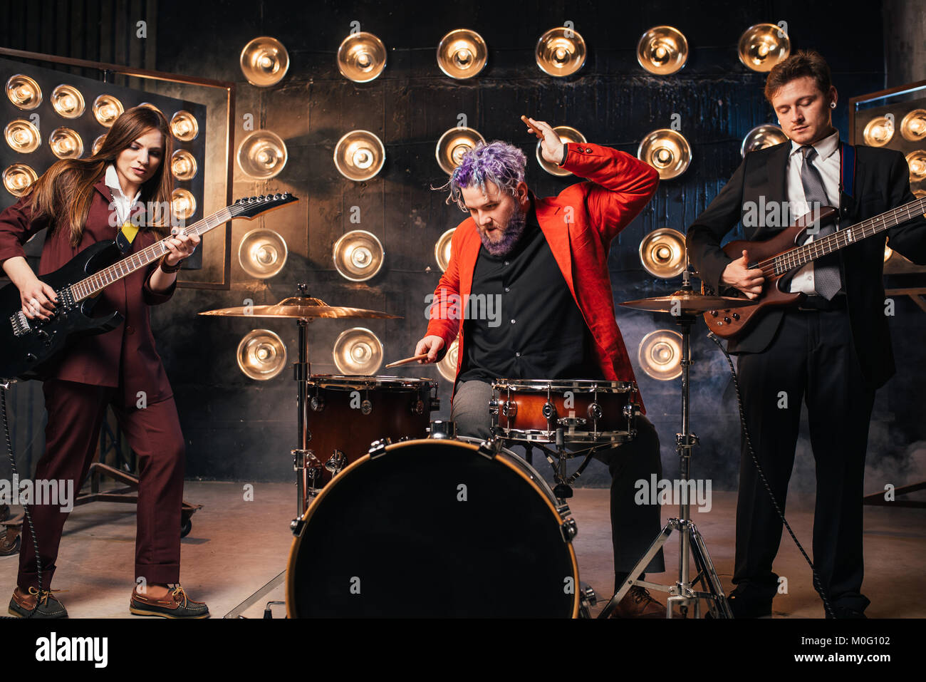 Musicians in suits on the stage with lights, retro style. Guitarists and drummer Stock Photo