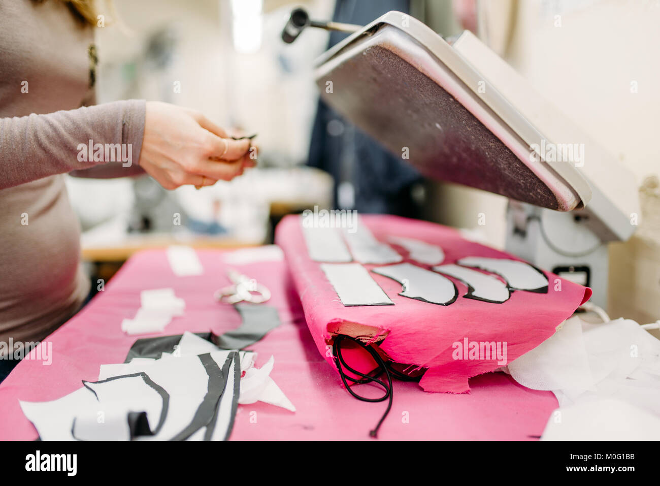 Clothes designer work with dress pattern on steam press, manufacture on sewing factory