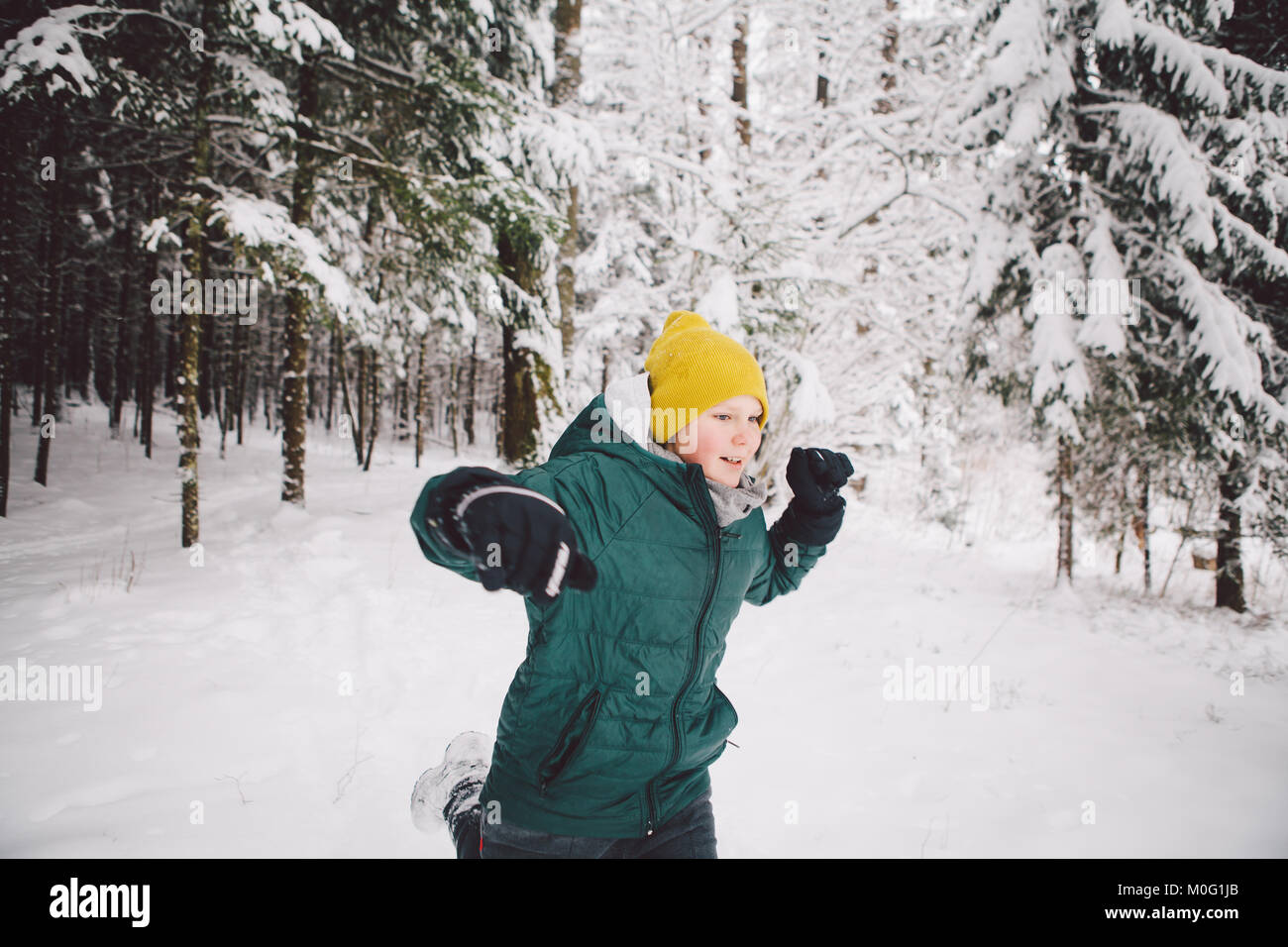 A teenage boy runs in a winter forest full of deep snow. Stock Photo