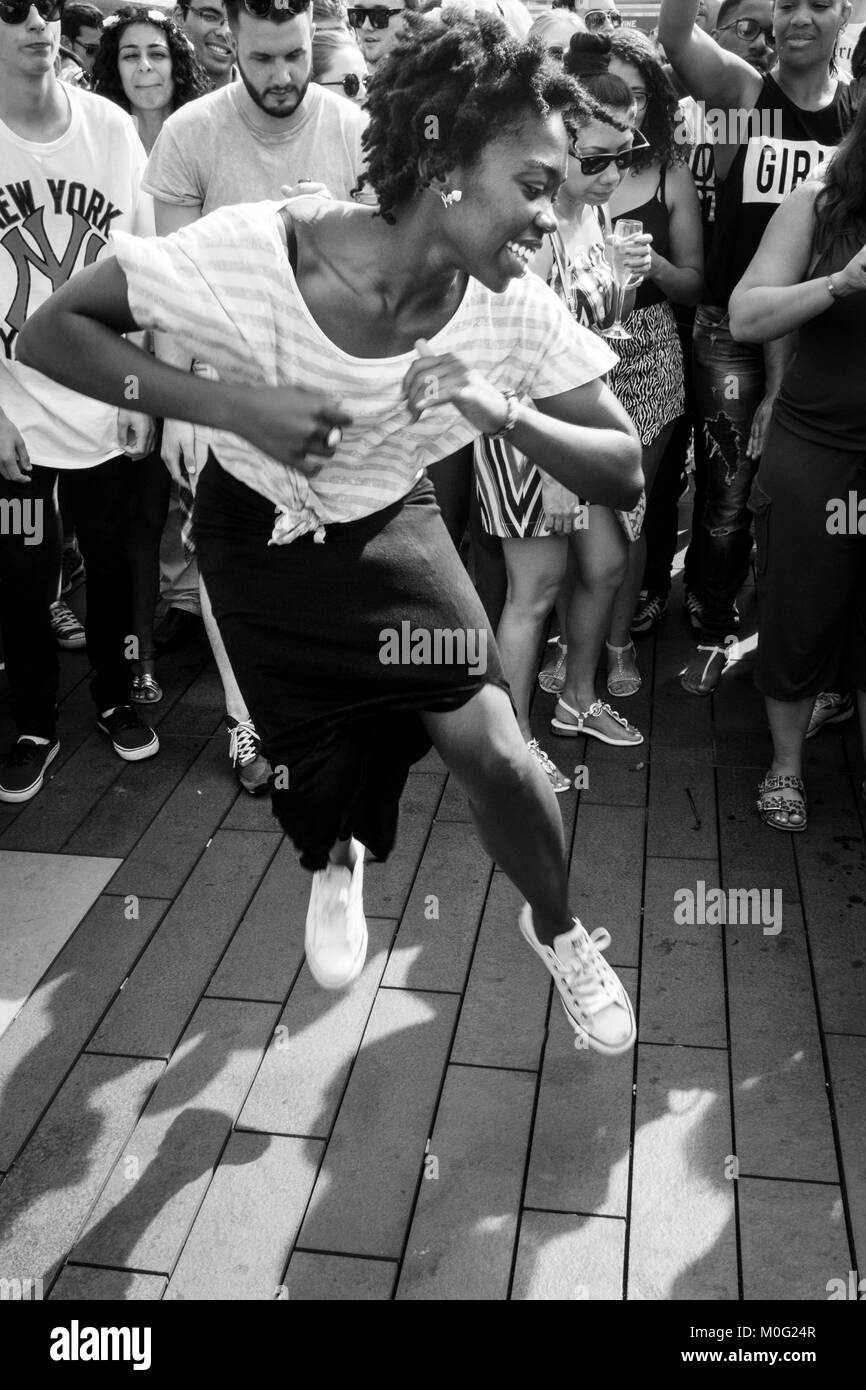 London black and white street photography: Young woman dancing at block party. Stock Photo