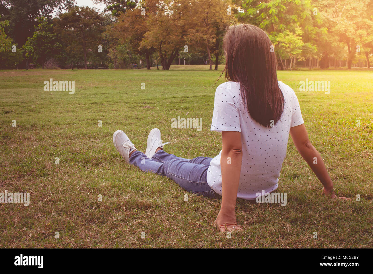 Woman relaxing and lies on green grass in the park in vintage style. Stock Photo