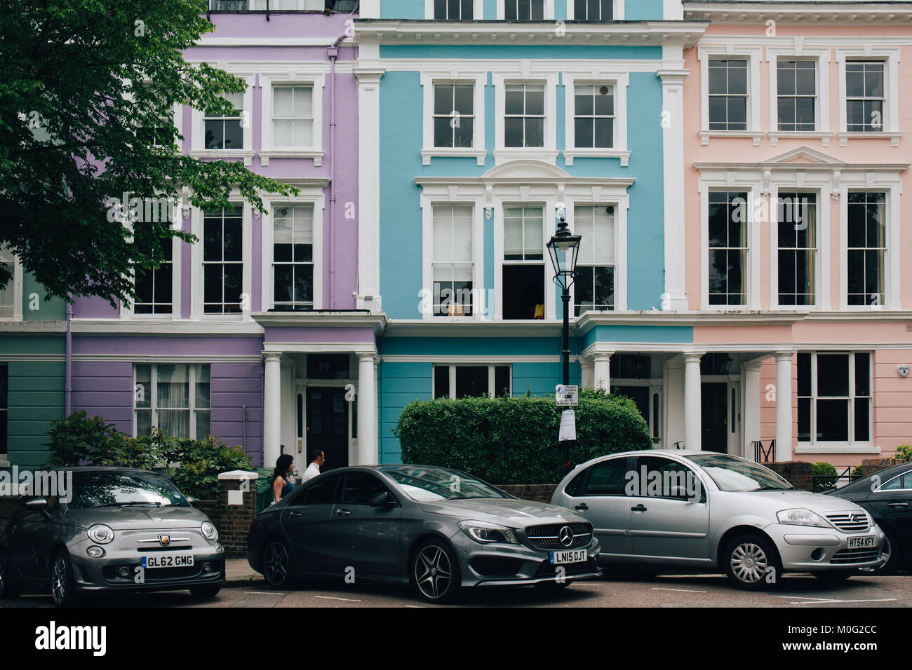 People walk past colourful terraced houses of Primrose Hill. Primrose