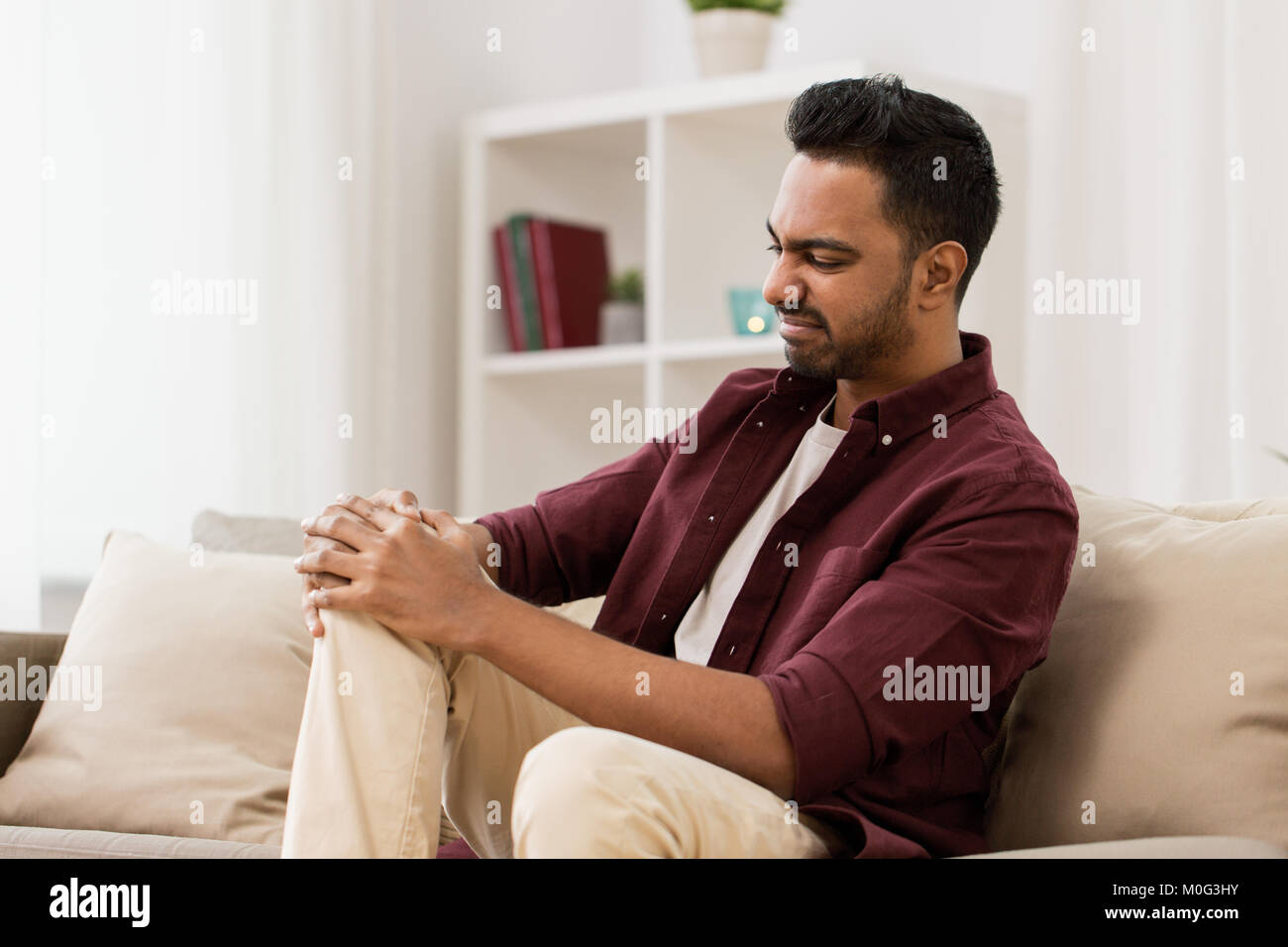 unhappy man suffering from pain in leg at home Stock Photo - Alamy