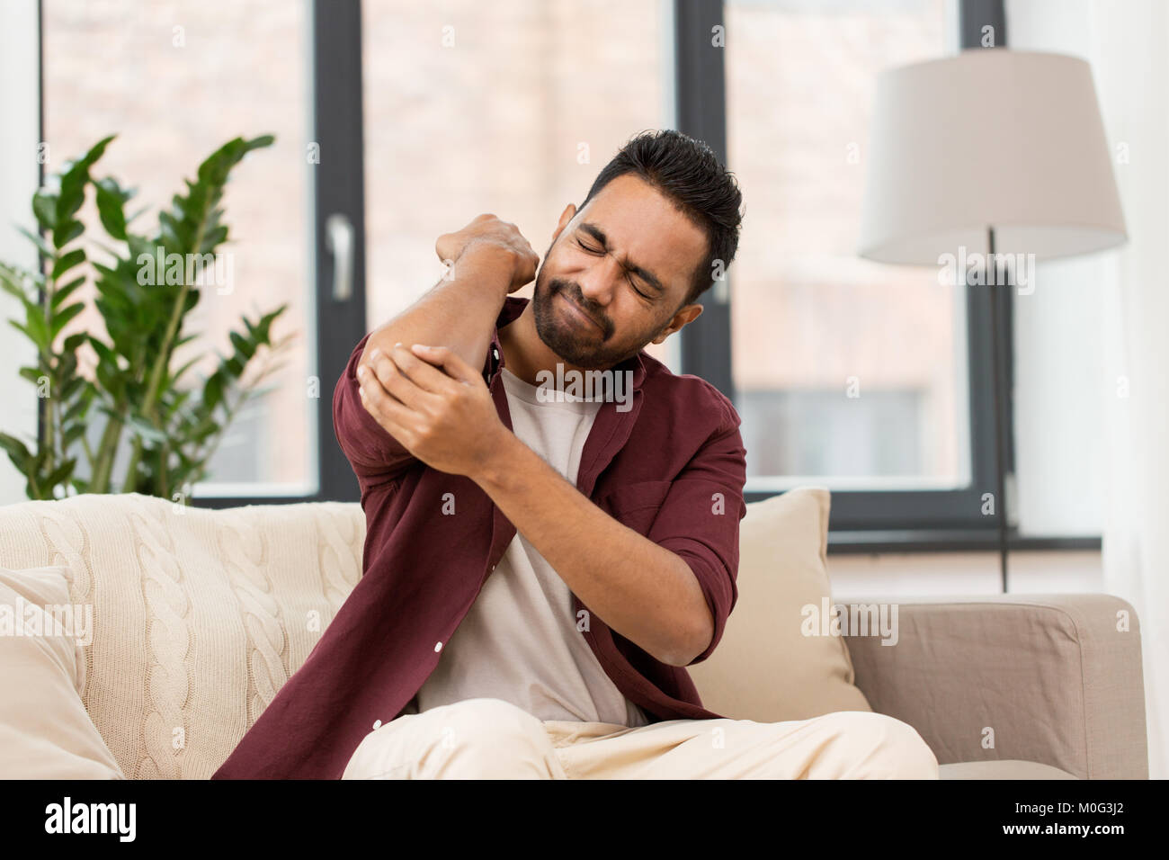 unhappy man suffering from pain in hand at home Stock Photo - Alamy