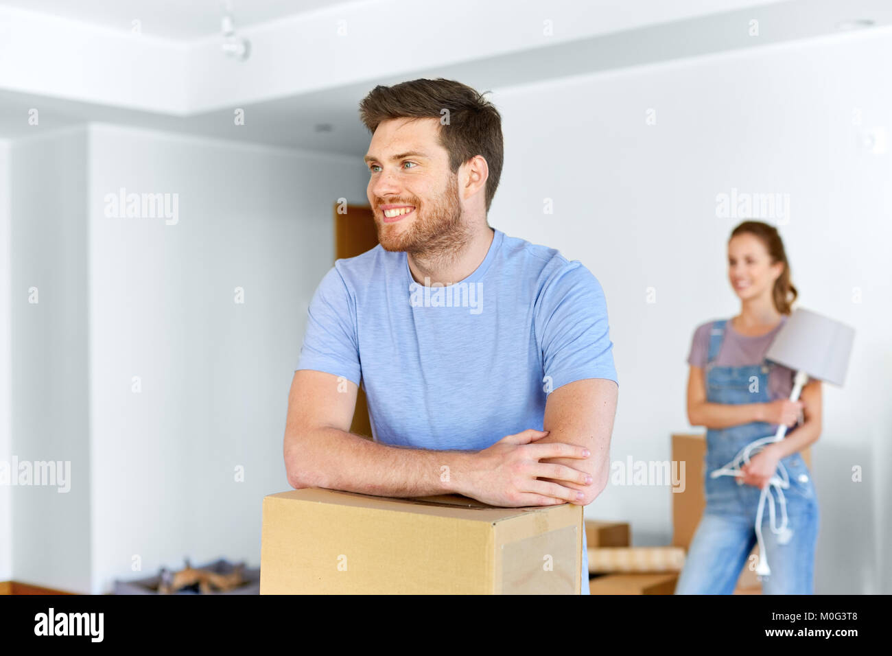happy couple with boxes moving to new home Stock Photo - Alamy