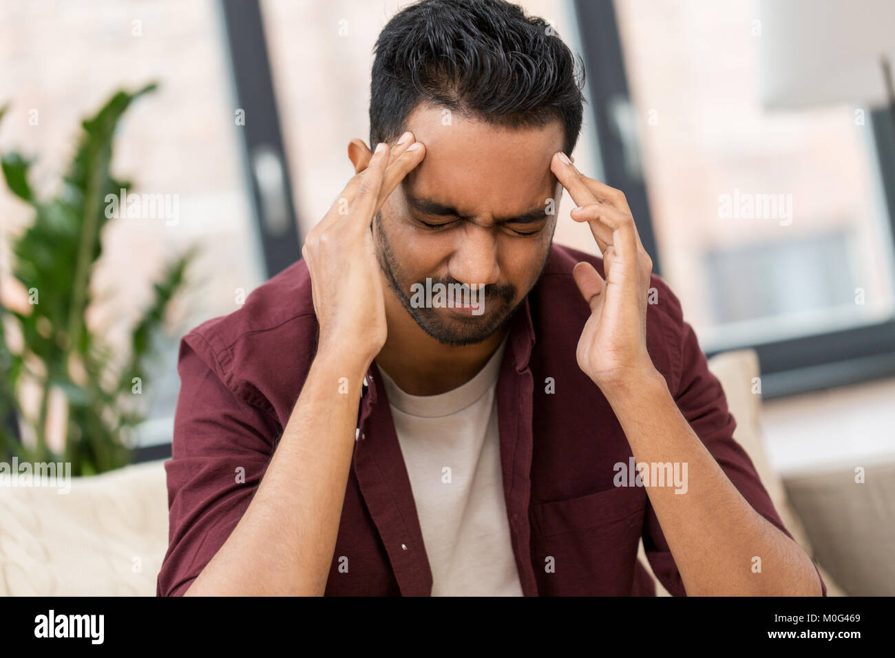 unhappy man suffering from head ache at home Stock Photo - Alamy