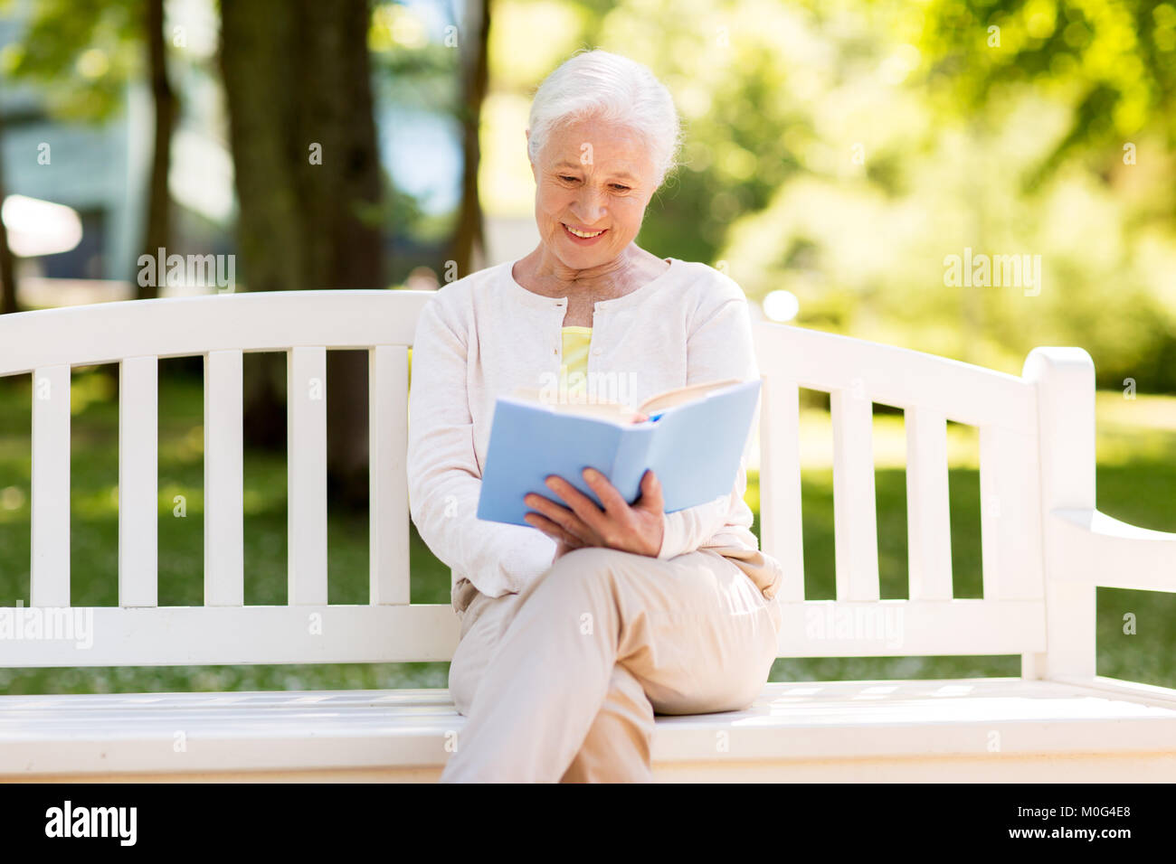 happy senior woman reading book at summer park Stock Photo - Alamy
