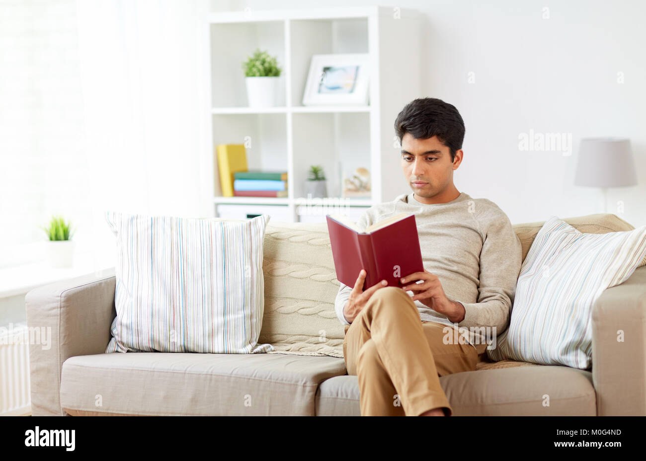 man sitting on sofa and reading book at home Stock Photo Alamy